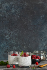 Fototapeta na wymiar Chia pudding with yogurt and raspberries in a glass on concrete background