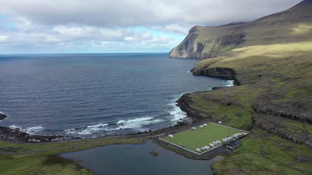 Flying over an old football field on the coast near Eidi in Faroe Islands