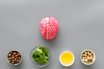Energy food for brain work with peanut, hazelnut, seed-oil, spinage on gray background top view