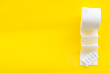 Proctology concept with toilet paper roll and rectal suppository on yellow background top view space for text