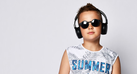 Teen handsome man smiling and laughing listening to music in headphones in a T-shirt with an inscription summer on a white background.