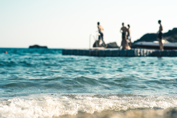 Floating platform in the sea, with teenagers having fun, out of focus