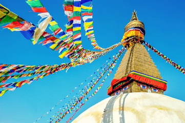 Bodhnath stupa in kathmandu with buddha eyes and prayer flags on clear Blue sky background.