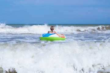 Fototapeta na wymiar Girl teenager on an inflatable circle in the sea, ocean. Swim during the waves.