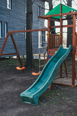 Blue plastic children's slide on a wooden game complex. Children's playground without anyone