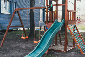 Blue plastic children's slide on a wooden game complex. Children's playground without anyone