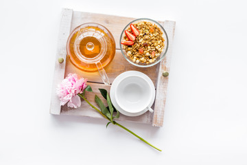 Breakfast in bed with granola, tea and fruit on tray on white background top view