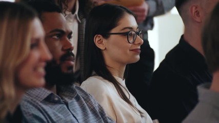 Happy young multiethnic business people sit in the audience listening to seminar at modern office conference close-up.