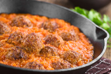 Homemade beef meatballs in fresh tomato sauce in cast-iron skillet (Selective Focus, Focus one third into the sauce)