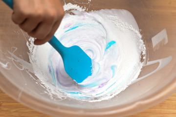 Children at home making homemade slime. Focus on hands mixing the ingredients