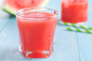 Refreshing watermelon juice on blue wood (Selective Focus, Focus on the front of the glass rim)