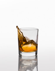 Whiskey splash on elegant glass isolated on white background