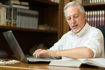 Man using his laptop while reading a book