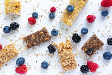 Pattern with cereal bars and blueberries, blackberries and raspberries with oatmeal. Healthy snacks and breakfasts