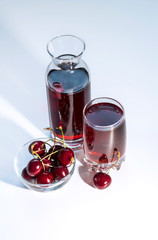 Sour cherry bowl with a carafe and a cherry juice on a white background, close up	