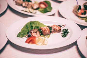 salmon kebab on a wooden skewer and other dishes for a family dinner in the restauran