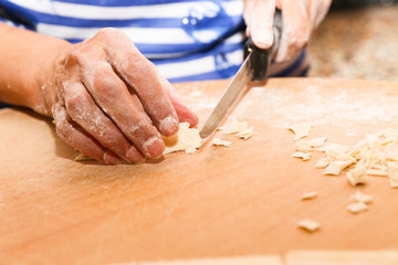 Side view woman's hands make Turkish Ravioli on table. Plates of traditional Turkish food. manti      