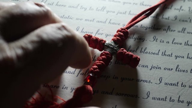 Fingers tapping on love letter and cross