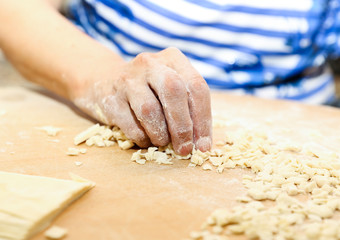 Side view woman's hands make Turkish Ravioli on table. Plates of traditional Turkish food. manti      