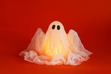 Fototapeta na wymiar Halloween ghost of starch and gauze on orange background. Gift idea, decor Halloween.