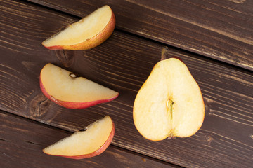 Group of one half three slices of fresh dark red pear anjou flatlay on brown wood