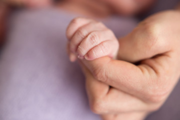 Newborn baby clenched fingers of his mother's finger