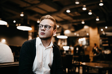 hipster man with glasses sitting in a cozy cafe