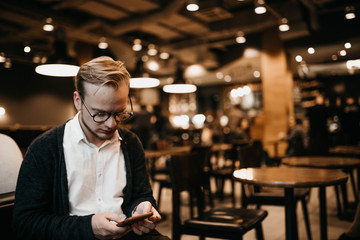 hipster man with glasses sitting in a cozy cafe