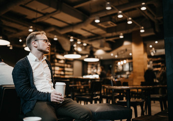 hipster man with glasses sitting in a cozy cafe