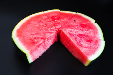A large slice of watermelon divided into smaller pieces, flat, red, isolated on a black background, as a data chart.