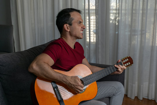 Man playing guitar in the living room and gnashing their teeth.