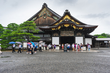 Tourists at the entrance in the Nijo castle in Kyoto in rain with colorful umbrellas during rainy season in Japan