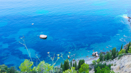 Seascape view of a white rock in a blue and turquoise lagoon with two fisherman and a small boat ...