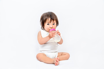 白背景で座り1人哺乳瓶でミルクを飲む女の子の赤ちゃん。育児,子育て,成長,発達イメージ