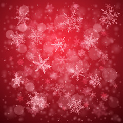 Christmas background of complex blurred and clear falling snowflakes in red colors with bokeh effect