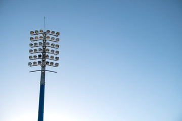 Sports stadium light tower during the day, set against a blue sky.