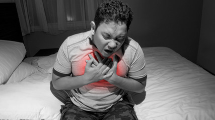 Man having heart attack on bed at midnight, chest pain, hard to breath, depression concept