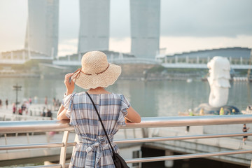Young Woman traveling with hat in the morning, happy Asian traveler visit in Singapore city...