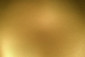 Light shining on gold metallic plate in dark room, abstract texture background