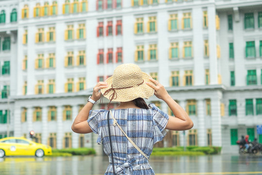 Young Woman traveling with hat, happy Asian traveler visit at rainbow colorful building in Clarke Quay, Singapore. landmark and popular for tourist attractions. Asia Travel concept