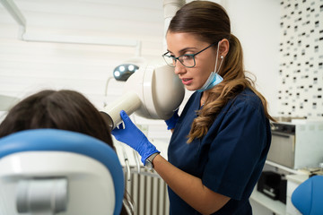 Woman dentist / technician doing teeth x-ray to a patient in chair 