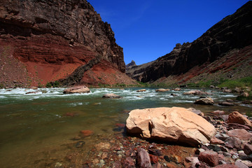 Hance Rapids in Grand Canyon National Park, Arizona, with red canyon walls under a deep blue sky.