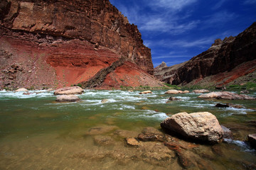 Hance Rapids in Grand Canyon National Park, Arizona, with red canyon walls under a deep blue sky.