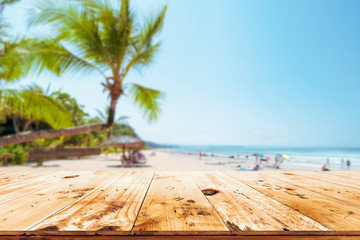 Top of wood table with seascape, palm tree, calm sea and sky at tropical beach background. Empty...