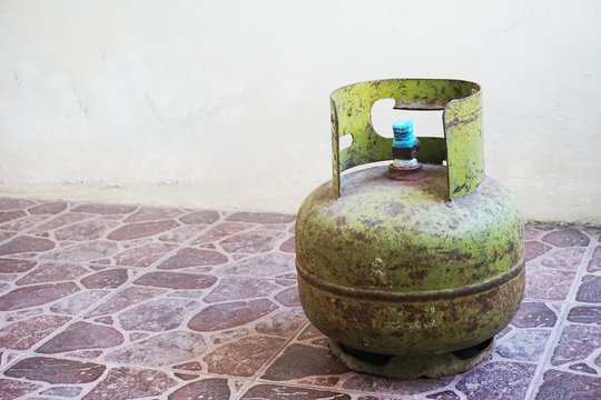 rust rust greenness lpg propane buthane fuel gas cylinder on the vintage brownish stone pattern floor tiles