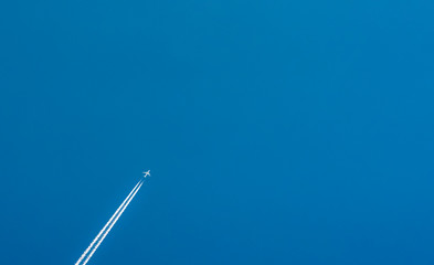 Airplane with white condensation tracks. Jet plane on clear blue sky with vapor trail. Travel by airplane concept. Trails of exhaust gas from airplane engine. Aircraft with white stripes.