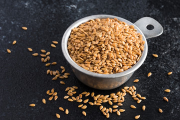 Whole Gold Flaxseeds Spilled from a Measuring Cup