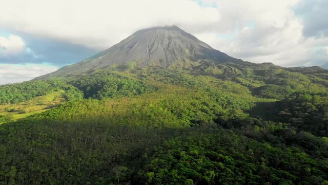 Arenal Volcano, Costa Rica, with cloud covering cone, push aerial view