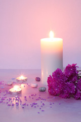 Candlelight and pink flowers on pink background, romantic feelings concept.