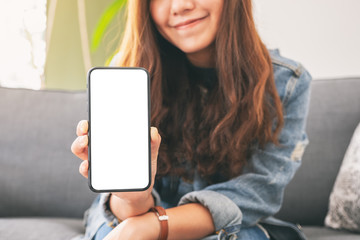 Mockup image of a woman holding and showing black mobile phone with blank screen in cafe